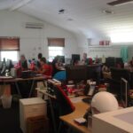 Office workers collaborate around a table as charts suggest steady business growth.